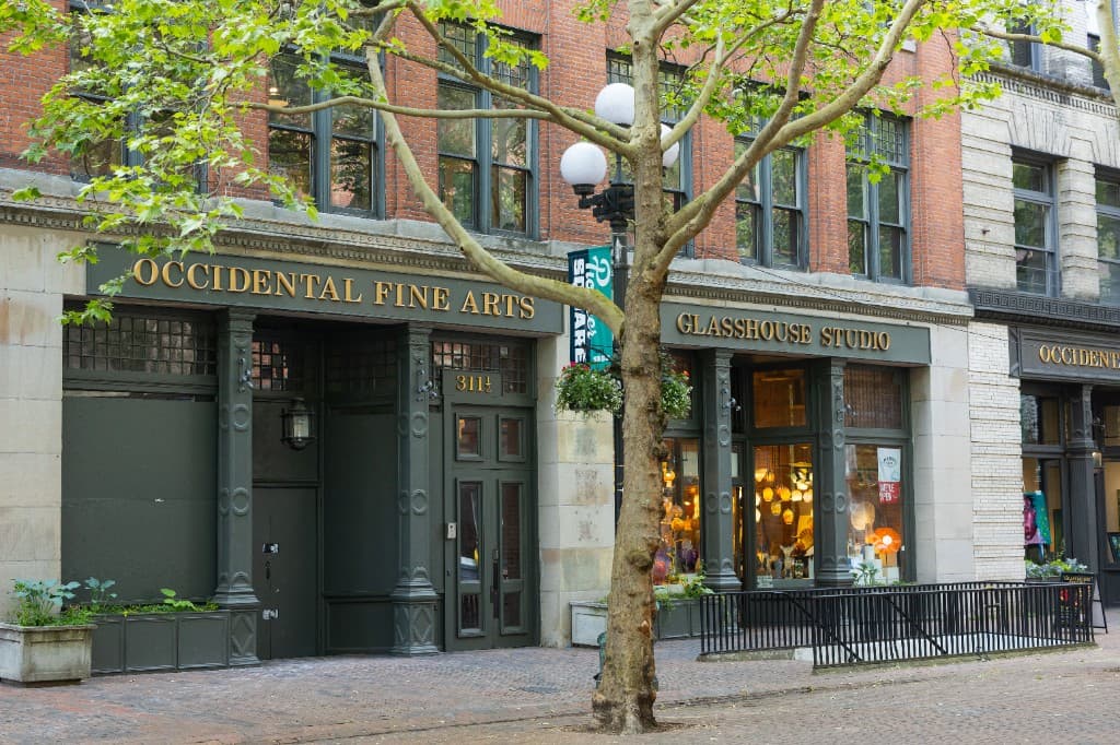 The Occidental Fine Arts Center and Glasshouse Studio storefronts on a tree-lined Pioneer Square block in Seattle.
